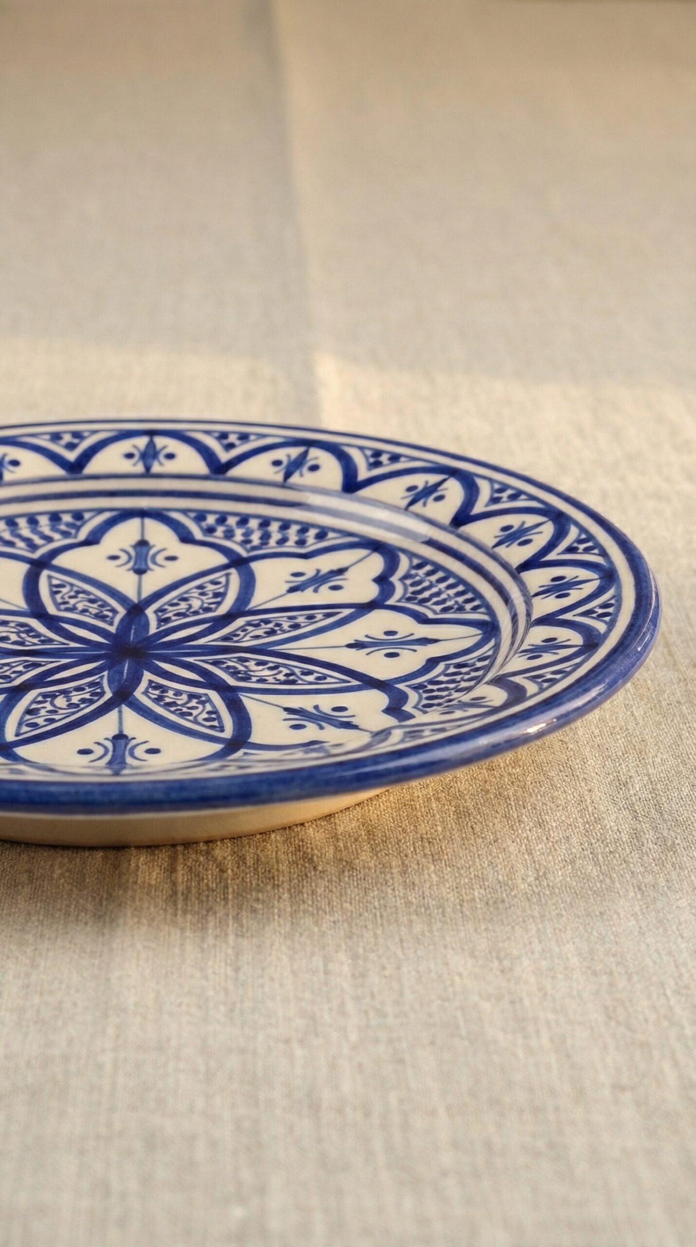 Plato de cerámica marroquí de 21cm pintado a mano. Diseño geométrico floral en tonos azul claro, coral y azafrán sobre fondo blanco crema. Acabado esmaltado brillante